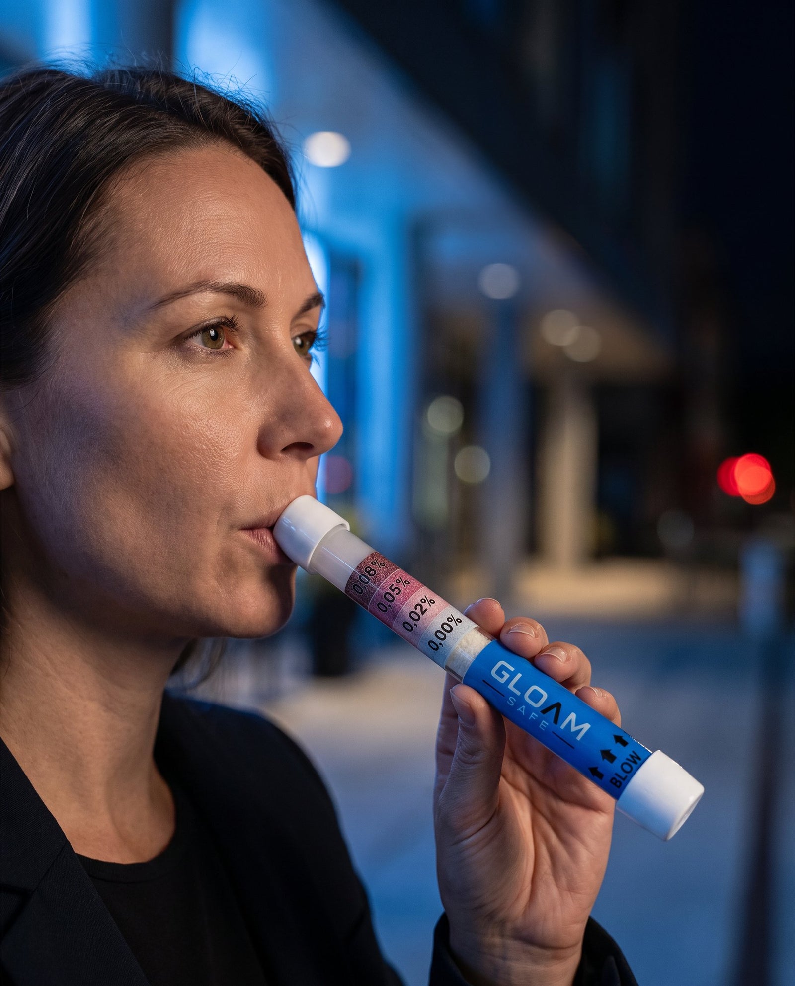Person using a Gloam Safe breathalyser on a city street at night